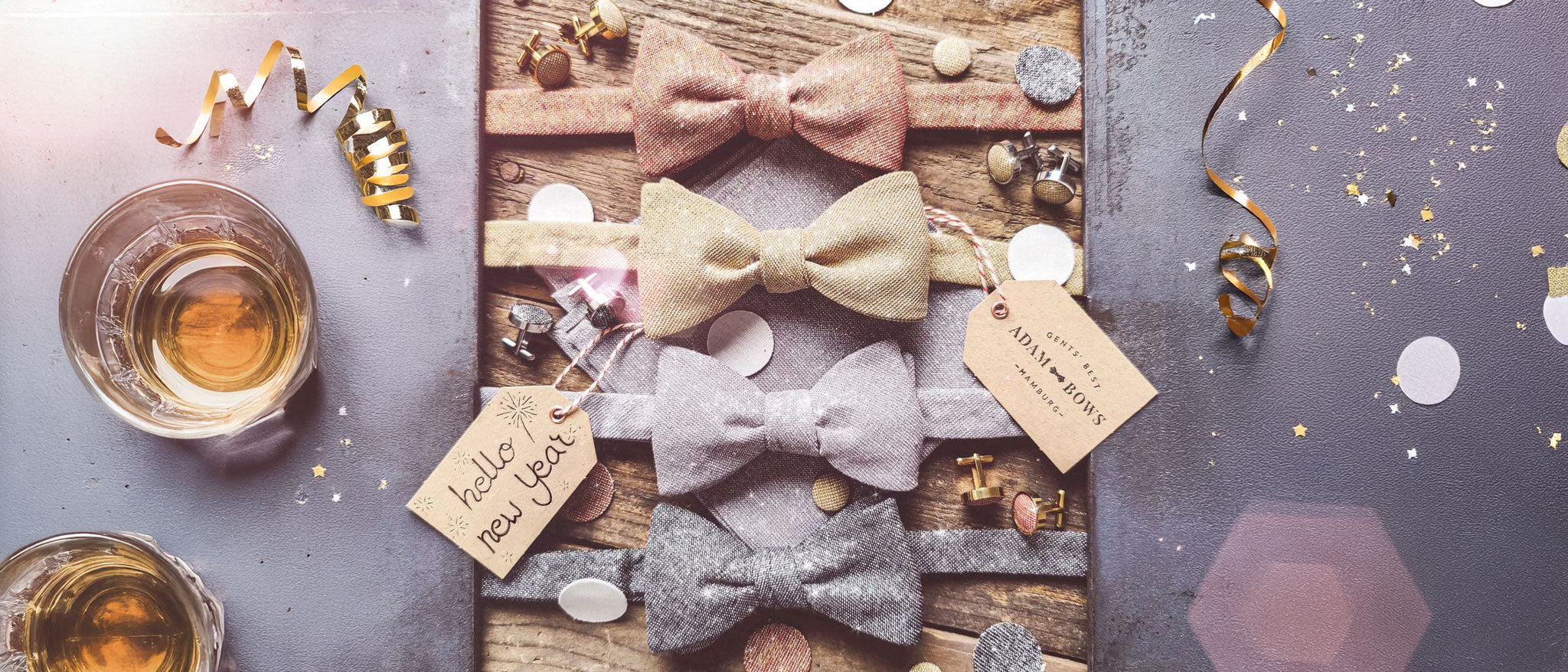 Glitzernde Silvester-Fliegen in Kupfer, Gold, Silber und Schwarz auf einem festlichen Tisch mit Party-Deko.