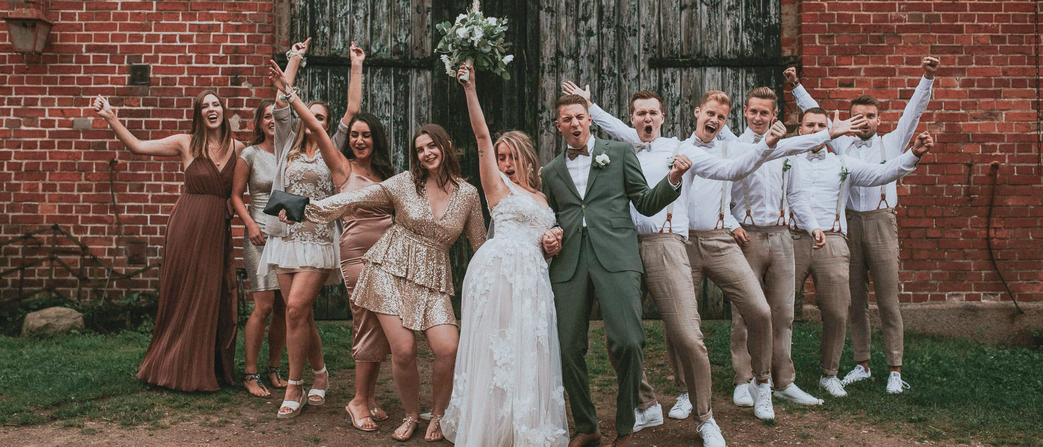 Braut und Bräutigam zwischen Brautjungfern und Groomsmen auf Landhochzeit. Bräutigam mit passendem Outfit zu den Groomsmen.
